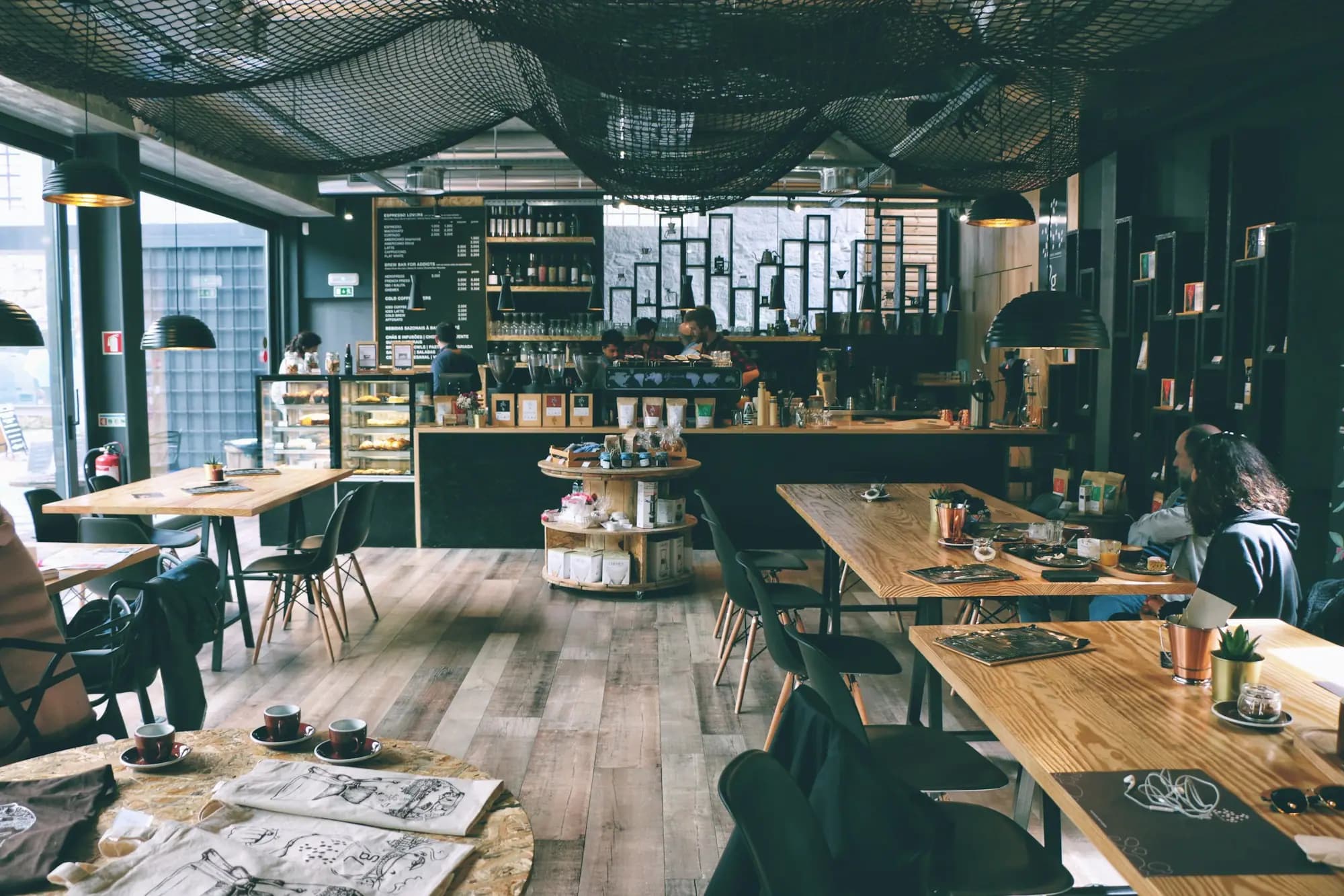 Interior de una cafetería llena, con clientes conversando en las mesas