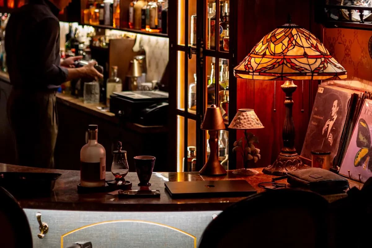 Barra de bar con botellas iluminadas y ambiente nocturno